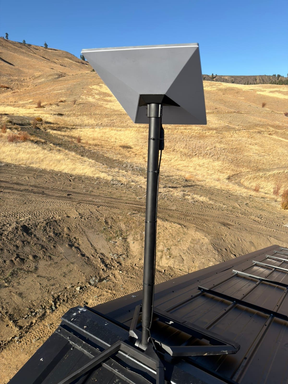 Pole-mounted Starlink dish above a metal roof